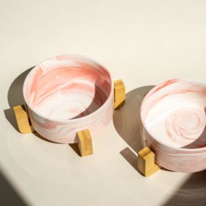Two pink ceramic pet bowls on bamboo tripods